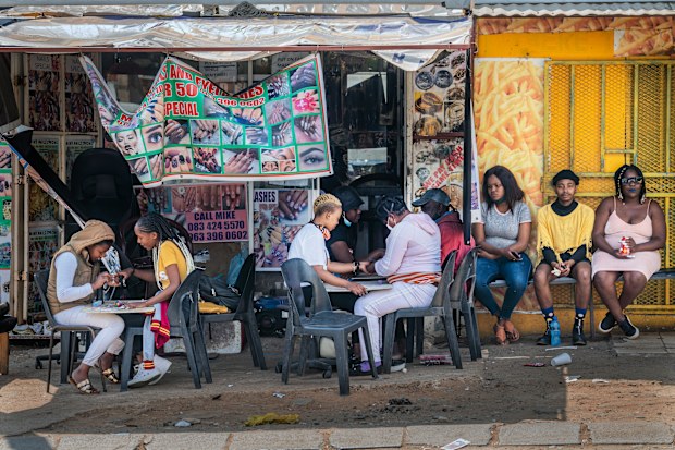 Customers have their nails done near the Baragwanath taxi rank in Soweto, South Africa ahead of restrictions opening up.