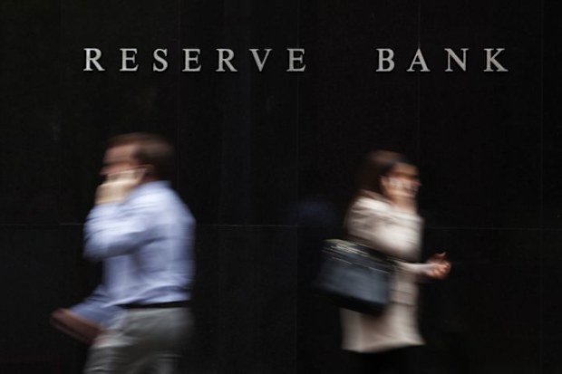 Two people on the phone walking in opposite directions outside the Reserve Bank of Australia, Sydney. The photo is taken with a deliberate blur.