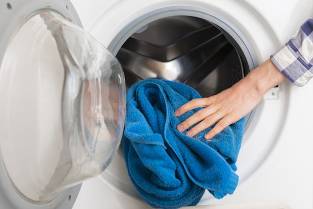 persons hand put towels in the washing machine
