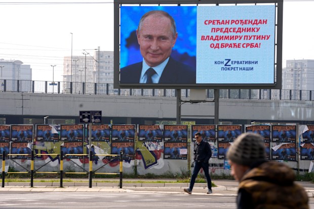 People walk past a big screen showing Russian President Vladimir Putin and reading: "Happy birthday to President Vladimir Putin from the Serb brethren!", in Belgrade, Serbia, Friday, Oct. 7, 2022. 