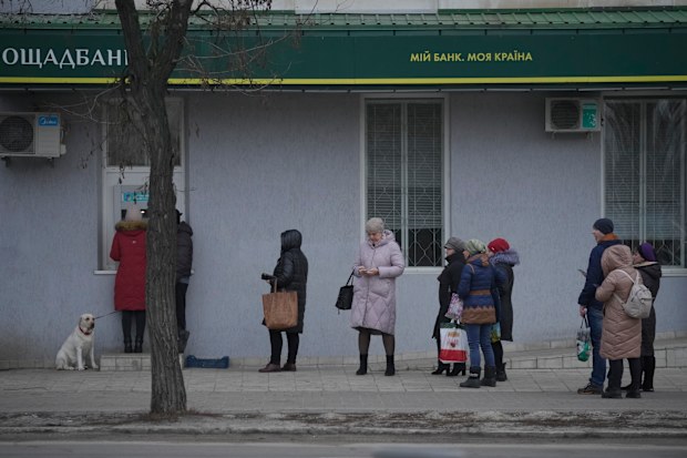 People queue to use an ATM machine outside in Sievierodonetsk, the Luhansk region, eastern Ukraine, Thursday, Feb. 24, 2022. 