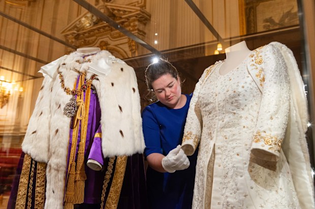 Curator Sally Goodsir makes final adjustments to The Queen's Coronation Dress next to The King's Robe of Estate