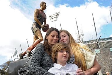 The Stynes family pose in front of a statue of Jim. (AAP)