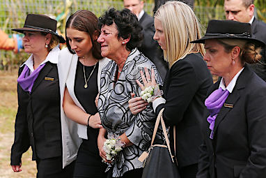 Hughes' mother, Virginia Hughes, with daughter Megan Hughes (L) follows behind the coffin.
