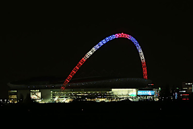 The famous arc of Wembley Stadium lights up in the French colours.