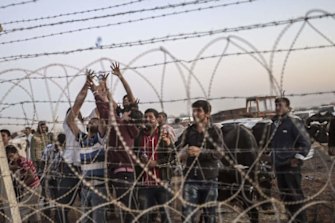 Syrian Kurds try to grab water thrown from Turkey near the border with Syria as they wait to take care of their animals at the southeastern town of Suruc in Sanliurfa province.