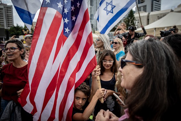 A boy holds an American flag as Israelis react to the news of the Gaza peace deal at Hostages Square on October 09, 2025 in Tel Aviv, Israel. 