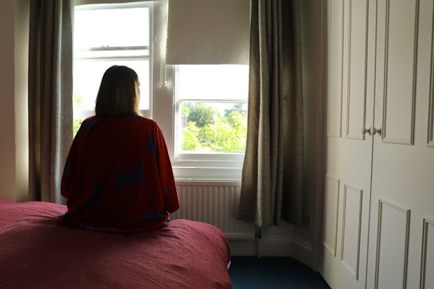 Rear view of a caucasian woman seated on the bedroom during lockdown coronavirus