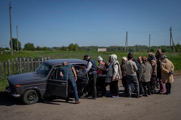 Villagers queue to buy cigarettes and bread from a peddler in the village of Staryi Saltiv, east Kharkiv, Ukraine, Friday, May 20, 2022. The village formerly occupied by Russian forces is back under Ukrainian control, albeit very close to the front line and under constant shelling. (AP Photo/Bernat Armangue)