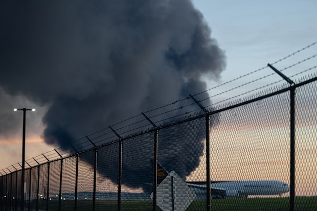 A UPS Boeing 737 is seen parked while a plume of smoke from the nearby UPS cargo plane crash is seen at Louisville Muhammad Ali International Airport on Tuesday, Nov. 4, 2025, in Louisville, Ky. (AP Photo/Jon Cherry)