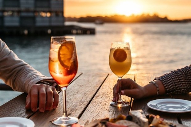 A couple enjoying a drink at sunset overlooking Sydney Harbour.