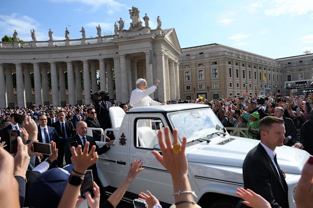Pope Leo XIV waves as he arrives ahead of the Inauguration Mass.