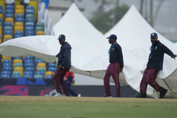 Ground staff cover the pitch as rains stops an ICC Men's T20 World Cup cricket match between England and Scotland' at Kensington Oval in Bridgetown, Barbados.