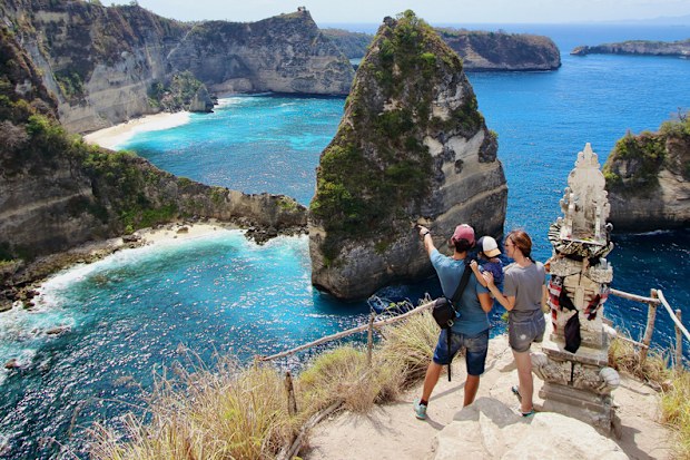 Young parents and little kid enjoying the views in Thousand Islands Viewpoint, on of the most amazing spots in Nusa Penida Island, Indonesia, Bali.