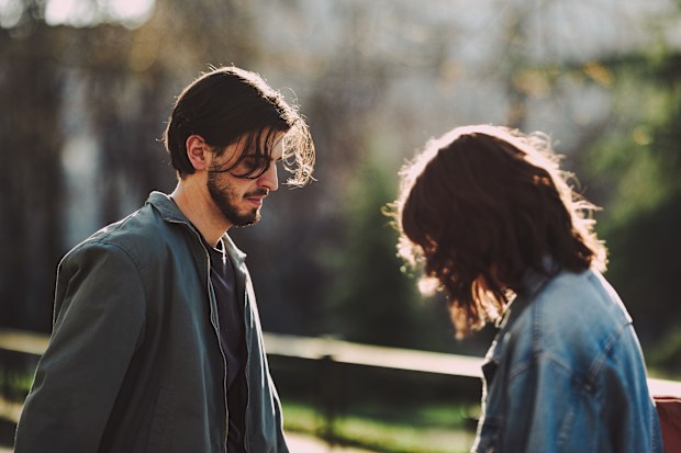 Boyfriend and girlfriend looking down while standing together on street