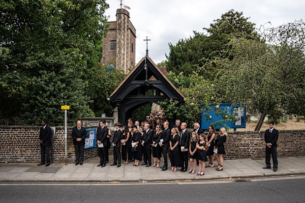 Friends and family look on as the cortege for Dame Deborah James leaves following her funeral at St Mary's Church on July 20, 2022 in Barnes, England.  
