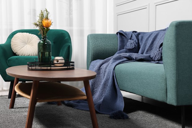Comfortable sofa, blanket, table and armchair in living room