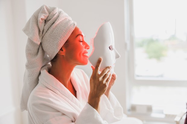 Woman using LED face mask at home