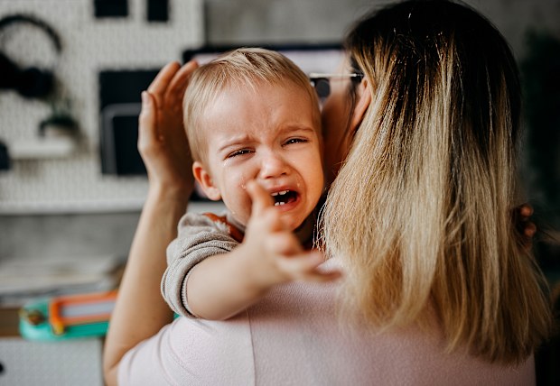 Cute little baby boy crying in his mother arms