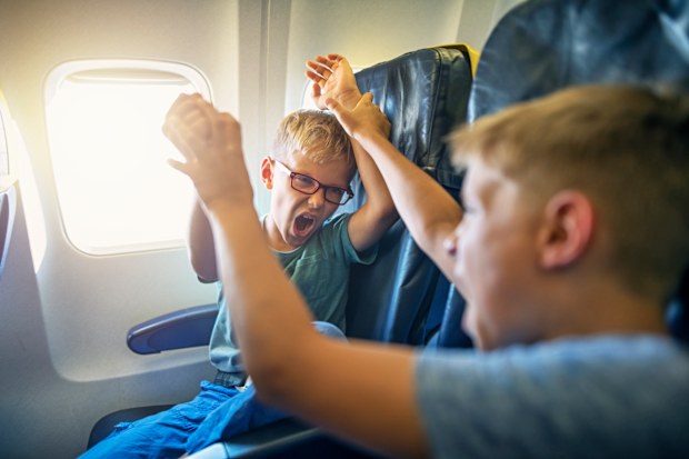 Two naughty boys travelling by plane. The boys are fighting and yelling. Naughty kids are a nightmare for their parents and other passengers. 