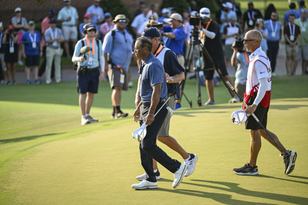 Tiger Woods walks with caddie Lance Bennett after finishing play on the 18th hole.