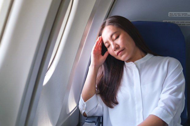 woman can't sleep on plane, tired, headache