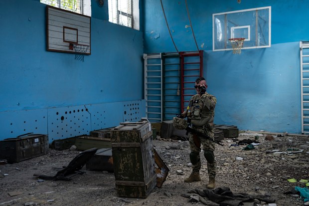 A Ukrainian serviceman inspects a school damaged during a battle between Russian and Ukrainian forces in the village of Vilkhivka, on the outskirts of Kharkiv, in eastern Ukraine, Friday, May 20, 2022. (AP Photo/Bernat Armangue)
