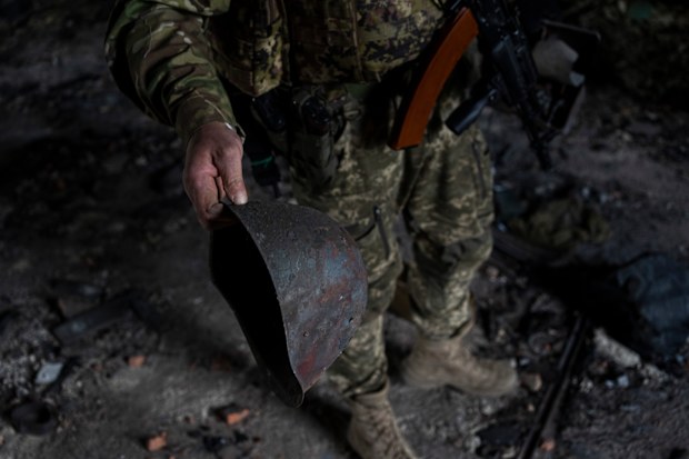 A Ukrainian serviceman holds the helmet used by Russian troops inside a school damaged during a battle between Russian and Ukrainian forces in the village of Vilkhivka, on the outskirts of Kharkiv, in eastern Ukraine, Friday, May 20, 2022. (AP Photo/Bernat Armangue)