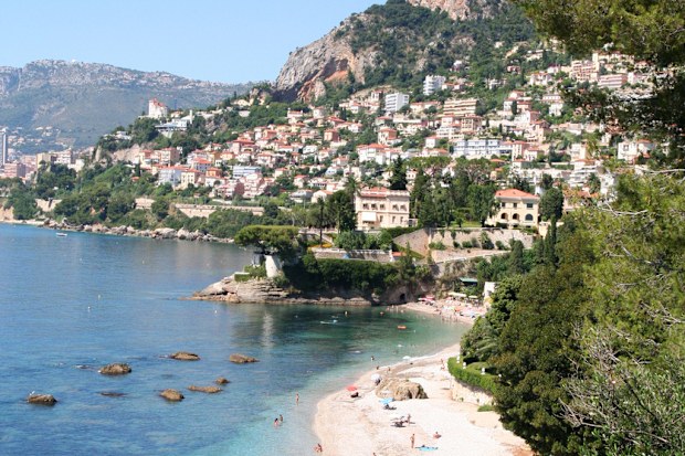 A small beach on the French Riviera with the town of Beausoleil in the background. Clear blue water is very inviting on a hot summer day.