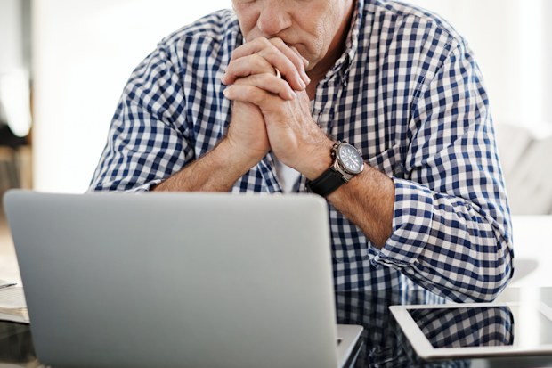 Shot of a mature man looking anxious while working on a laptop at home