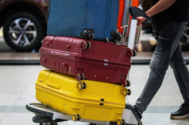 Person wheeling suitcases on a trolley at the airport