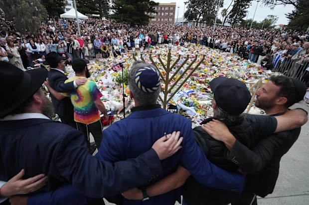 Mourners gather at a menorah lighting ceremony at a floral memorial for victims of Sunday's shooting, at the Bondi Pavilion.