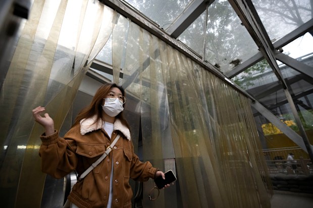 A commuter wearing a face mask walks out of a subway station in the central business district in Beijing, Friday, Oct. 28, 2022. 