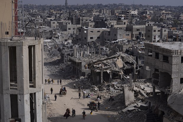 Palestinians walk through the destruction in the wake of an Israeli air and ground offensive in Khan Younis, southern Gaza Strip, Monday, April 8, 2024. 