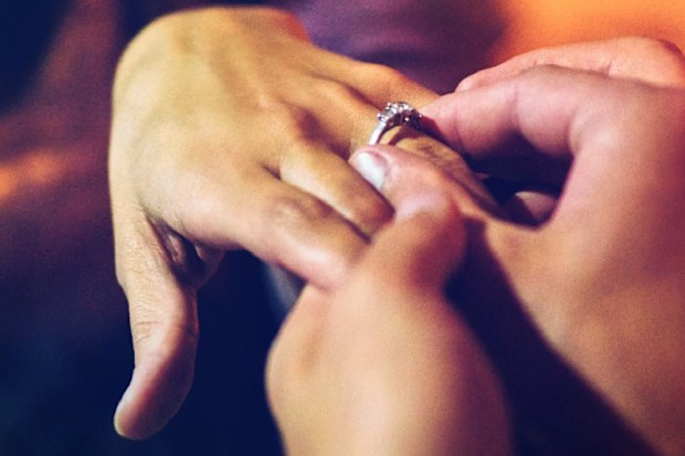 Man placing ring on woman's finger following proposal
