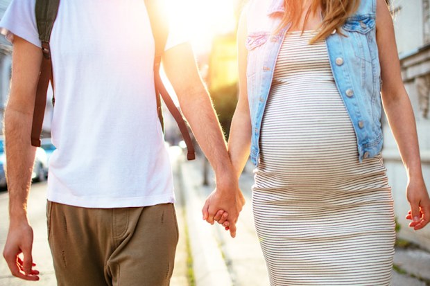 Man walking hand in hand with pregnant partner