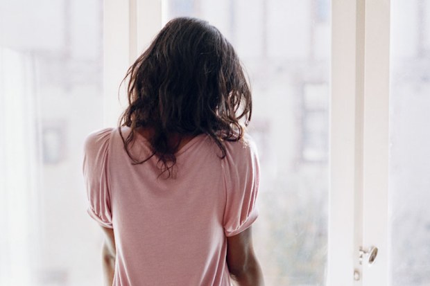 Young woman looking out window sadly