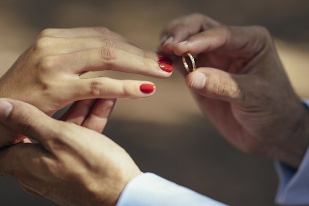 Groom putting wedding ring on finger of bride, close up