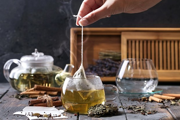 Woman dipping a tea bag into hot water.