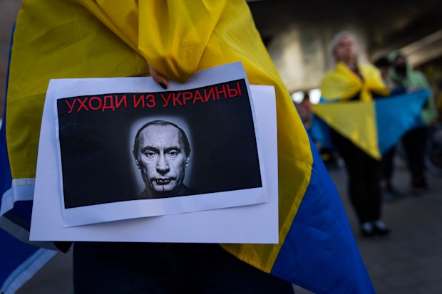 FILE - A demonstrator holds a banner depicting Russian President Vladimir Putin during a pro-Ukraine protest outside the Russian Embassy, after Russian troops have launched their anticipated attack on Ukraine, in Tel Aviv, Israel, Thursday, Feb. 24, 2022. Sign in Russian reads "get out of Ukraine". (AP Photo/Oded Balilty, File)
