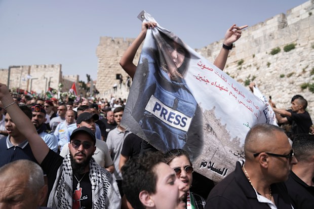 Mourners hold a banner depicting slain Al Jazeera veteran journalist Shireen Abu Akleh as they walk from the Old City of Jerusalem to her burial site, Friday, May 13, 2022. Abu Akleh, a Palestinian-American reporter who covered the Mideast conflict for more than 25 years, was shot dead Wednesday during an Israeli military raid in the West Bank town of Jenin.(AP Photo/Ariel Schalit)