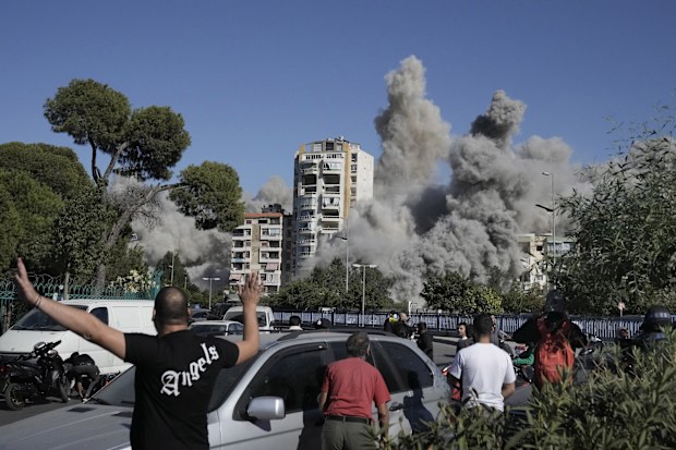 4 People react as smoke rises from a building that was hit by an Israeli missile in Ghobeiri, Beirut, Lebanon, Tuesday, Oct. 22, 2024. (AP Photo/Bilal Hussein)