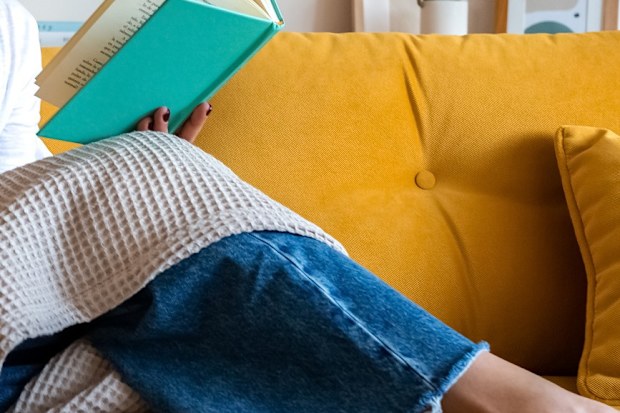 woman reading book on lounge
