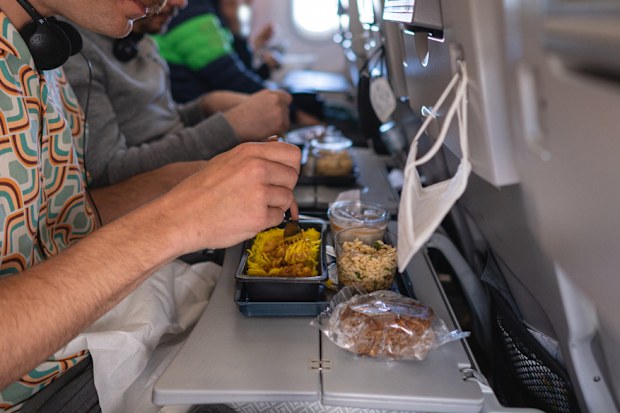 Side view of Caucasian male tourist having a meal at the airplane, while traveling - plane food