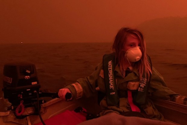 Finn Burns navigates a boat through thick smoke at Mallacoota, as fire advanced on the seaside Victorian town on December 31, 2019.