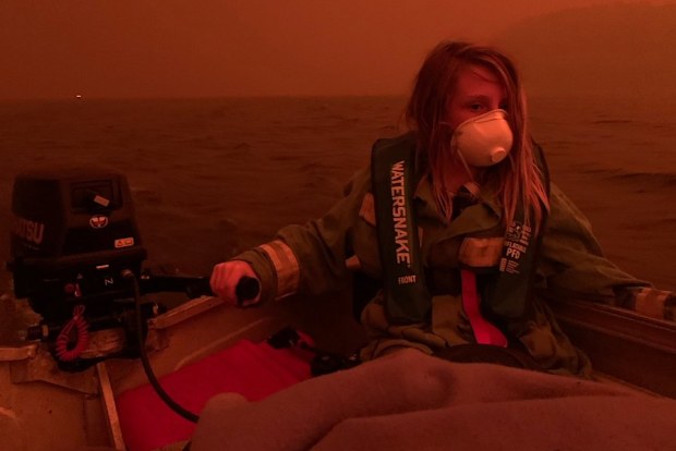 Finn Burns navigates a boat through thick smoke at Mallacoota, as fire advanced on the seaside Victorian town on December 31, 2019.
