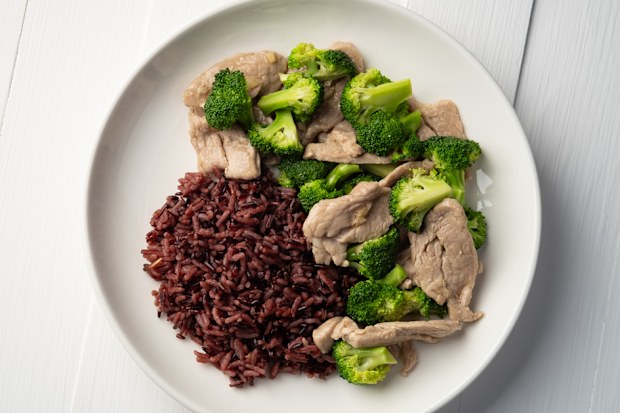 Cooked riceberry rice and Stir fried broccoli with pork tenderloin fillet in white plate.