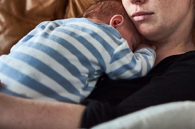 Tired mother holding baby on lounge.