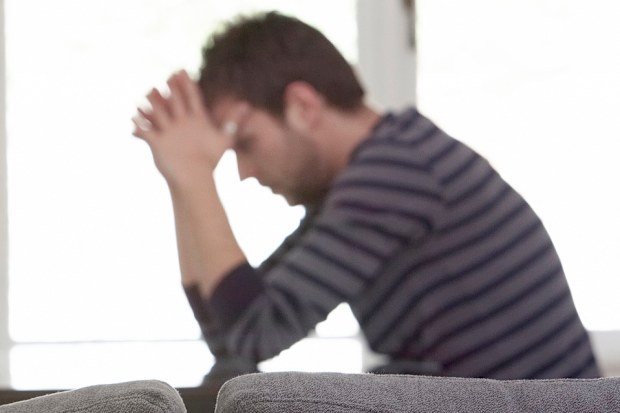 Man sitting at table with head in hands upset