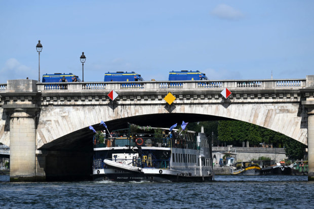 A test event for the Paris 2024 opening ceremony on the Seine while police guard the bridge.